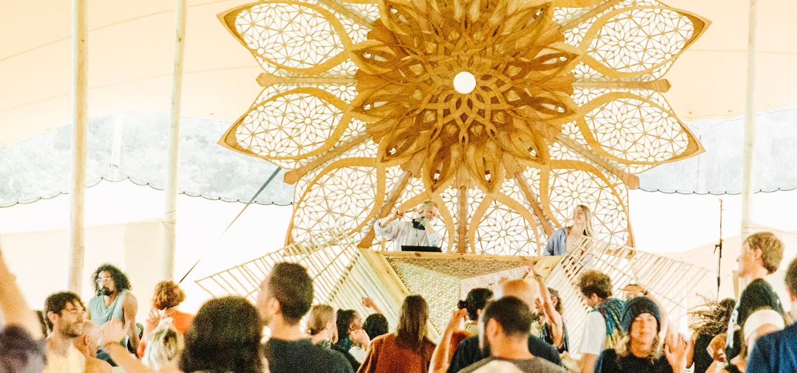 Dancers beneath a large wooden mandala at an ecstatic dance